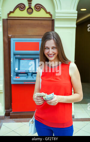 Young happy brunette woman retirer de l'argent de carte de crédit à un guichet automatique Banque D'Images