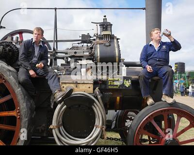 Près de Malvern, Royaume-Uni. 29 juillet, 2016. Chris Perkin de Inkberrow (à gauche) et Paul Davies d'Astwood Bank de prendre une pause de s'occuper d'une vitesse 19133 Burrell traction à vapeur à la vapeur juste près de Welland dans le Worcestershire Malvern Royaume-uni. Le moteur a été exporté en Nouvelle-Zélande comme une nouvelle machine et a été renvoyé au Royaume-Uni pour rénovation et sera retournée à son propriétaire dans Wakanui après Chris et Paul ont fait en sorte que tout fonctionne comme il le devrait. Crédit : Richard Sheppard/Alamy Live News Banque D'Images