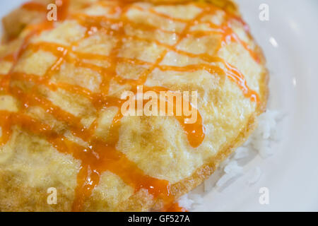Omelette dans un plat de riz blanc et la sauce tomate. Banque D'Images