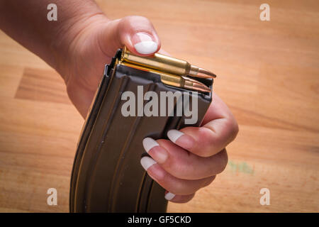 Chargement de munitions en femme .223/556 Magazine sur la surface la surface du bois Banque D'Images