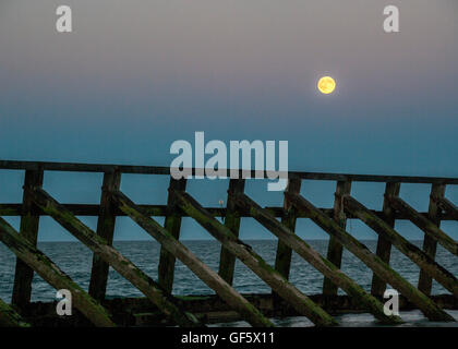 Pleine lune s'élève au-dessus de Littlehampton West Beach West Sussex UK. Structure bois en premier plan Banque D'Images