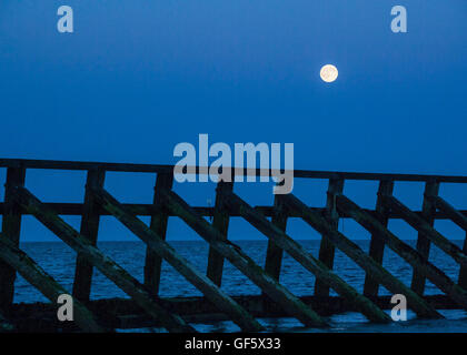 Pleine lune s'élève au-dessus de Littlehampton West Beach West Sussex UK. Structure bois en premier plan Banque D'Images