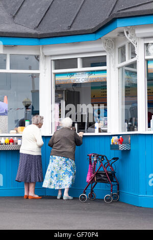 Dames âgées acheter de la nourriture à un kiosque sur le jetée de Llandudno dans la station balnéaire du nord du Pays de Galles, Royaume-Uni Banque D'Images