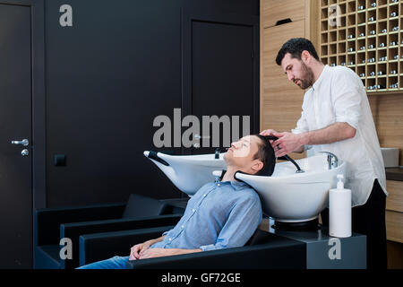 Hairstylist Coiffure Cheveux Client Laver - Young Man Relaxing In Hairdressing Salon de Banque D'Images