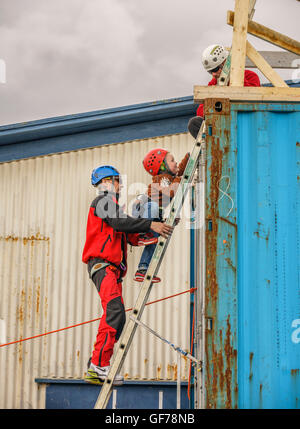 Jeune garçon monte jusqu'à repousser vers le bas de l'échelle des conteneurs d'expédition à l'Assemblée annuelle de Seaman's Festival, Hafnarfjordur, Islande Banque D'Images