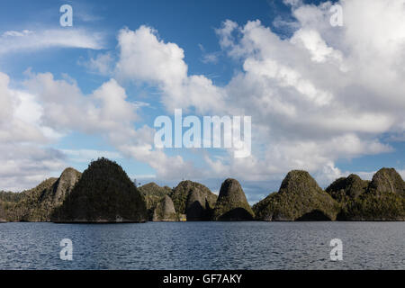 Îles calcaires escarpées entourant un lagon tropical, à distance à Wayag, Raja Ampat, en Indonésie. Banque D'Images