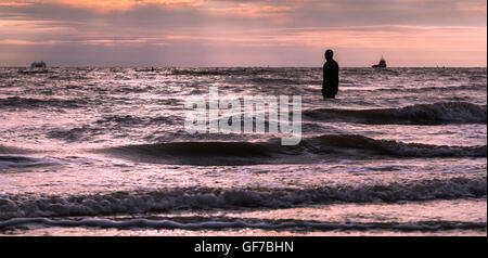 Jusqu'au tour des vagues autour des jambes d'un homme de fer avant le coucher du soleil sur la plage près de Crosby, Liverpool. Banque D'Images