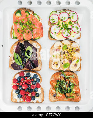 Petit-déjeuner sucré et salé assortiment de toasts. Des sandwichs avec des fruits, légumes, oeufs, saumon fumé blanc sur fond de cuisson Banque D'Images