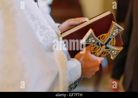 Belle croix d'or dans les mains des hommes de prêtre portant robe de cérémonie d'or à Christian église cathédrale, événement sacramentel saint. Banque D'Images