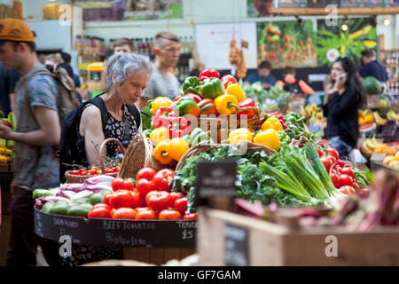 Une vieille dame la sélection des légumes dans un marché (Borough Market, London, UK) Banque D'Images