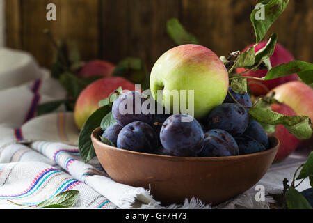Organique mûres des pommes et des prunes dans un bol en céramique Banque D'Images
