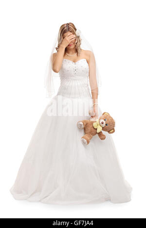 Verticale sur toute la longueur d'un coup triste young bride holding a teddy bear isolé sur fond blanc Banque D'Images