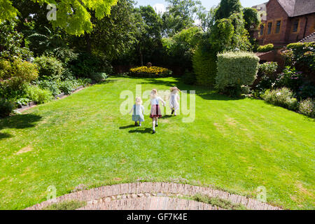 La maison et les jardins de Greyfriars avec 3 enfants / kids / kid en marche et de jouer sur la pelouse du jardin de l'herbe. Friar Street, Worcester. UK Banque D'Images