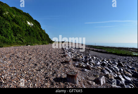 Plage de galets le long de la Manche, où l'eau bleue et claire remplit le ciel bleu clair à l'horizon Banque D'Images