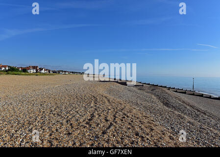 Plage de galets le long de la Manche, où l'eau bleue et claire remplit le ciel bleu clair à l'horizon Banque D'Images