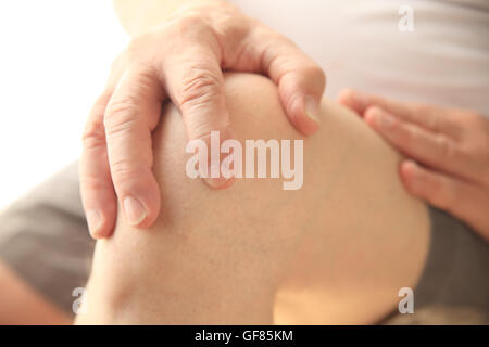 Man avec une main sur son genou douloureux Banque D'Images