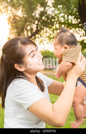 Bébé 2 mois d'asie se sentir heureux et sourit avec sa mère dans le jardin et le fond coucher de soleil