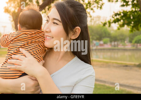 Bébé 2 mois d'asie se sentir heureux et sourit avec sa mère dans le jardin et le fond coucher de soleil