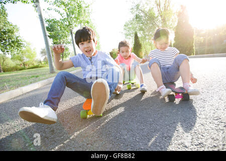 Heureux les enfants chinois assis sur une planche à roulettes Banque D'Images