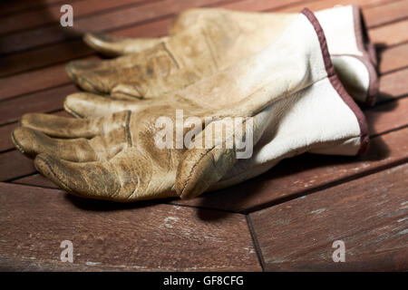 Porter des gants de travail en cuir sur une table d'extérieur en bois. Banque D'Images