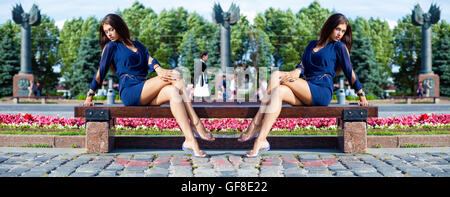 Belle jeune femme est assise sur un banc dans un parc d'été Banque D'Images