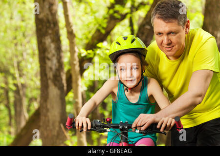 Happy girl learning to cycle avec son père Banque D'Images