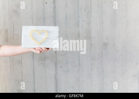 Femme tenant conseil avec coeur Banque D'Images