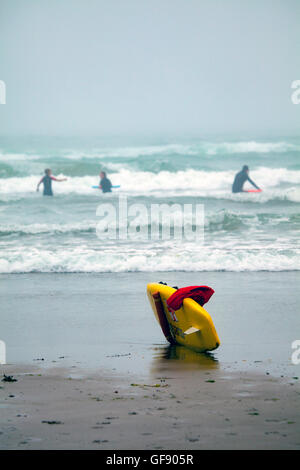 Surfers appréciant les courbes, de Whitsand Bay Cornwall, England UK avec une carte de sauveteur RNLI en premier plan Banque D'Images