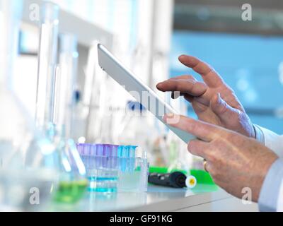 Parution de la propriété. Parution du modèle. Chercheur scientifique à l'aide d'une tablette numérique pour entrer des données dans un laboratoire pendant une expérience. Banque D'Images