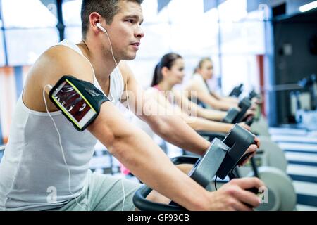Parution de la propriété. Parution du modèle. Jeune homme à l'écoute de la musique tout en s'entraîner dans la salle de sport. Banque D'Images