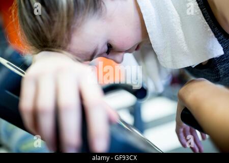 Parution de la propriété. Parution du modèle. Close-up of young woman posant sa tête sur machine d'exercice dans la salle de sport. Banque D'Images