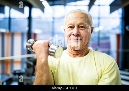 Parution de la propriété. Parution du modèle. Portrait of senior man holding dumbbell dans une salle de sport. Banque D'Images