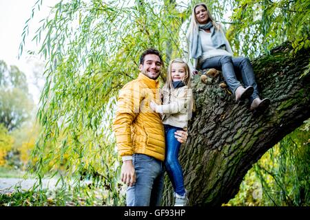 Parution du modèle. Père, mère fille comptable sitting on tree, smiling, portrait. Banque D'Images