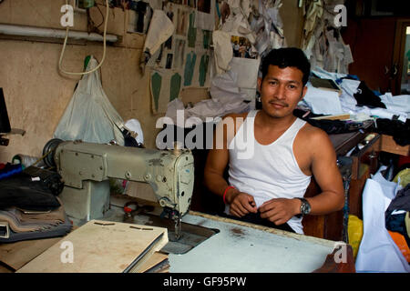 Un homme est assis à une machine à coudre alors que celui de tailleur dans un magasin à Phnom Penh, Cambodge. Banque D'Images