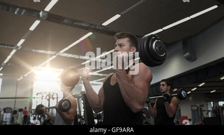 Groupe d'hommes flexing muscles avec barbell in gym Banque D'Images