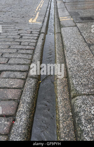 Street / drainage caniveau à Truro, Cornwall. Métaphore visuelle pour "l'argent en bas du drain' et le gaspillage de l'eau / le gaspillage de l'eau. Banque D'Images