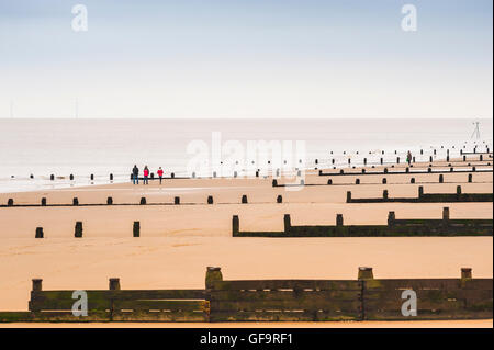 Côte d'Essex, vue sur un après-midi d'hiver d'une famille qui fait une promenade sur une plage déserte près de Frinton dans Essex, Angleterre, Royaume-Uni. Banque D'Images