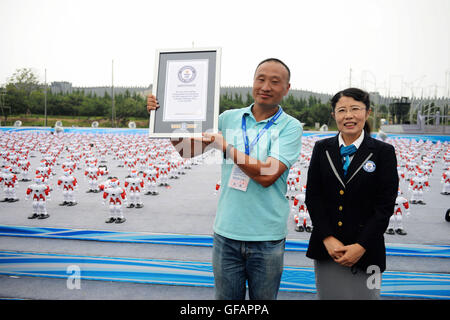 Qingdao, Chine, la province de Shandong. 30 juillet, 2016. Une femme membre du personnel de Guinness World Records délivre le certificat à l'organisateur d'une activité danse du robot au principal lieu d'exposition pour 2016 Qingdao International Beer Festival à Huangdao District de Qingdao, province de Shandong en Chine orientale, le 30 juillet 2016. Au total 1 007 robots dansé ensemble plus d'une minute d'ici samedi, établissant un nouveau record mondial Guinness. Credit : Yu Fangping/Xinhua/Alamy Live News Banque D'Images