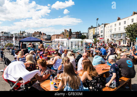 Front de l'Anglais à Ramsgate avec des gens assis à des tables et des chaises de prendre un verre au cours de temps très chaud en été. Banque D'Images