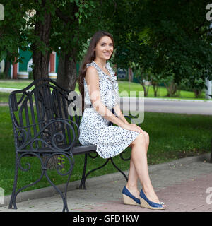 Belle jeune femme est assise sur un banc Banque D'Images