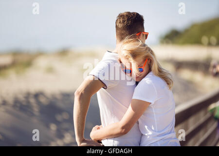 Jeune couple hugging sont par la barrière en bois sur la plage, l'heure d'été Banque D'Images