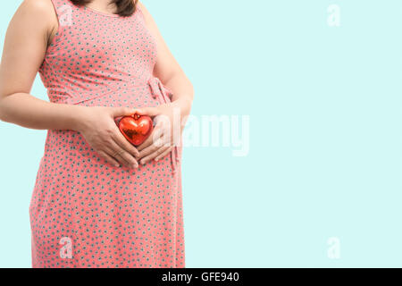 Pregnant woman holding gift ventre coeur. Grossesse en santé isoler sur fond bleu Banque D'Images