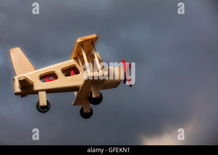 Avion en bois volant sous le ciel d'orage - vue latérale Banque D'Images