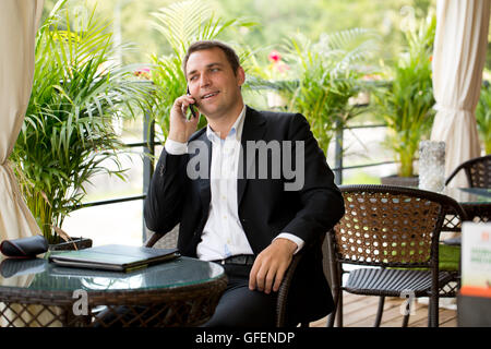 Happy businessman using mobile phone at outdoor restaurant d'été Banque D'Images