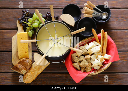 Set d'ustensiles traditionnels pour la fondue, avec du pain, du fromage et du raisin Banque D'Images