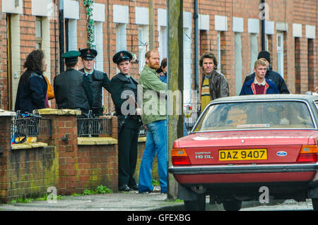 Belfast, Irlande du Nord. 18 déc 2014 - Acteurs habillés comme des Royal Ulster Constabulary (RUC) d'officiers républicains irlandais et se tenir sur une rue à Belfast au cours d'un tournage vidéo film. Banque D'Images