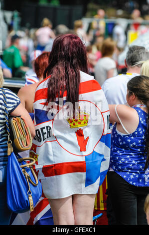 Une jeune fille regarde le défilé portant un grand drapeau. Banque D'Images