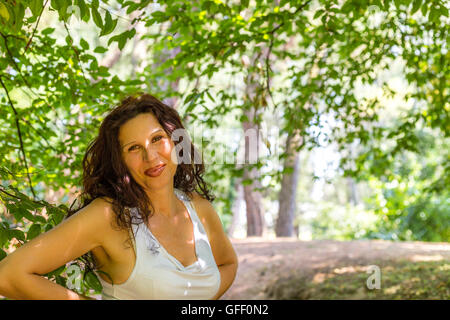 Close up of young woman chic busty smiling at the camera contre green garden background with copy space Banque D'Images