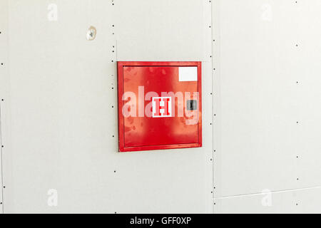 Cabinet d'incendie rouge avec éteindre l'équipement est placé dans un mur sec. Banque D'Images