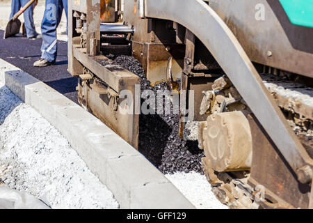 Détail de l'équipement industriel en collaboration avec l'asphalte. La route goudronnée portant la machine. L'épandeur d'asphalte. Banque D'Images